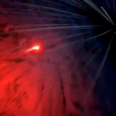 Man ties some sort of flare gun to his feet and jumps off a cliff in a wingsuit looking like a comet.