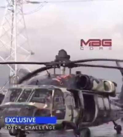 Man holds on to centre of spinning helicopter blades