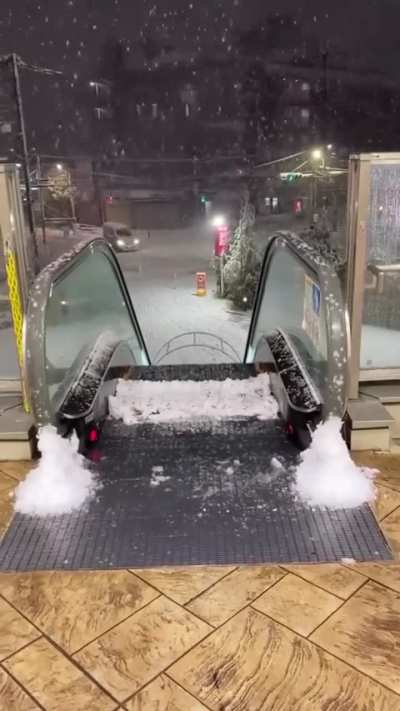 Outdoor escalator accumulating snow on the top step