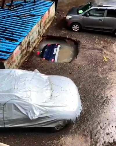 A car going down a sinkhole during rains..