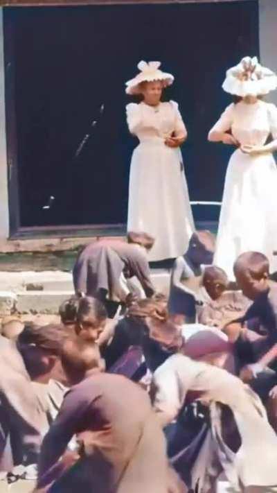 Wife and daughter of French Governer-General Paul Doumer throwing small coins and grains in front of children in French Indochina (today Vietnam), filmed in 1900 by Gabriel Veyre (AI enhanced)