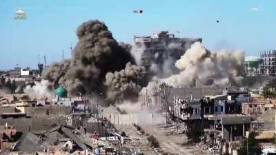 An ISIS SVBIED collapses a 8 story Iraqi Army held building after a bulldozer clears the way under heavy fire. May 2015.