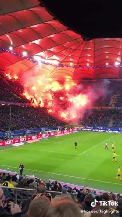 The flags look like a bunch of hands reaching out of hell, but it’s just football fans with flares