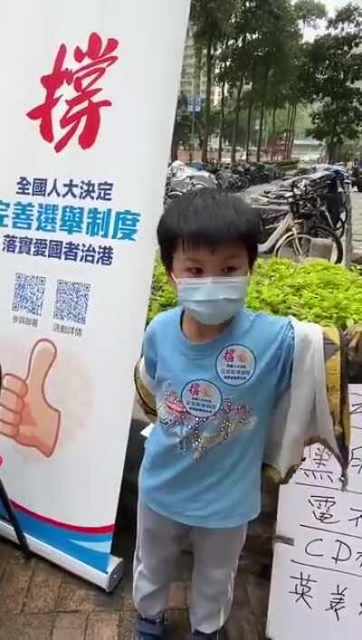An 8-year old kid in Hong Kong, next to a pro-Beijing poster: “We must support the country… We must support the government, and must not support the protesters… Our country must be ‘blue,’ not ‘yellow’ — because those are bad guys!”