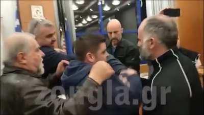 A furious man in Greece throws concrete from a collapsing ceiling of a public school (that endangered children) at city council officials.
