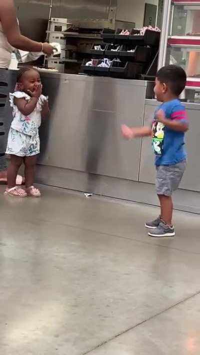 Little boy goofing around trying to get a smile from a little girl