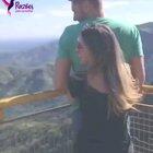 A woman lifting up her husband who can't stand on his own, so he can better appreciate the view.