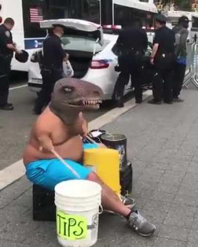 Midget dinosaur man with long legs plays buckets while man gets arrested by police