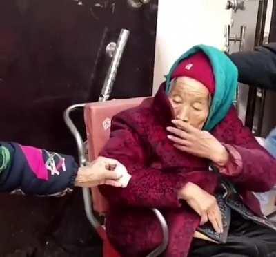 84-year-old daughter smiles after 107-year-old mother hands a sweet to her.