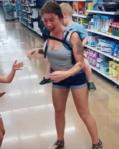 Toddler tickling his mom while strapped to her back