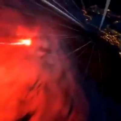 Man ties some sort of flare gun to his feet and jumps off a cliff in a wingsuit looking like a comet.