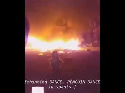 Just dudes singing around a fire while a penguin toy dances