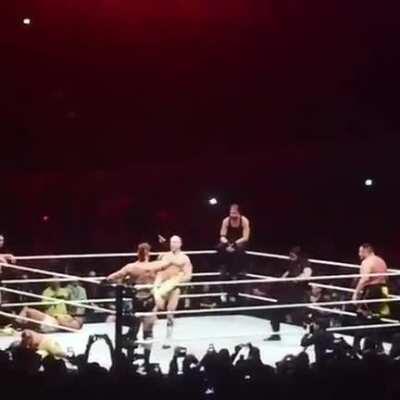 Seth Rollins jumping over Kofi while Cesaro performs the Cesaro Swing on him