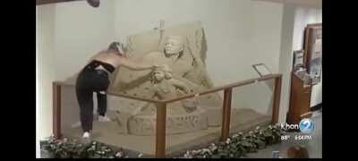 Two teens destroying a sand sculpture in a Waikiki hotel.