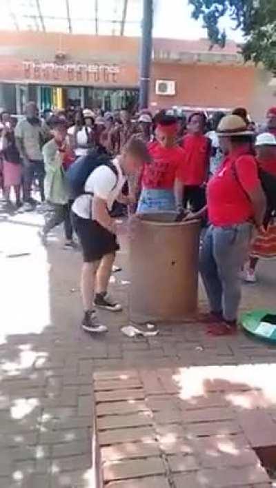 2 woman throw garbage on the ground while a guy tries to clean