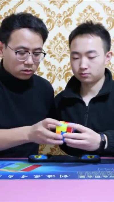 Two men (Xia Yan and Wang Penhcheng) speedcubing the same rubik's cube and break the world record (13.70 seconds)