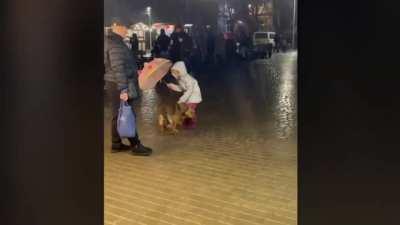 Five year old girl protects dog from rain with a umbrella