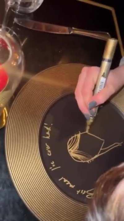Jenna signs a plate at a restaurant in Paris