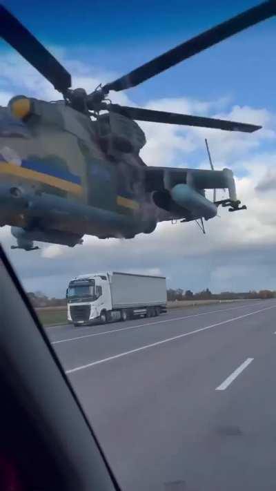 Ukrainian Army Aviation Mil Mi-24 Attack Helicopter flying at a dangerously low altitude over a highway
