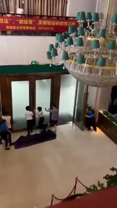 Hotel workers try to hold doors shut hit by powerful gusts of wind from super typhoon in Vietnam