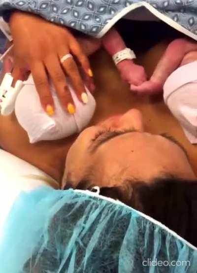 Two sisters hold hands right after birth