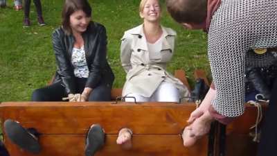 French renfaire tickling three girls one barefoot and the other two in socks. The barefoot blond gets tickled while the other two watch. When he goes to the next girl he puts a clamp on her foot and she laughs
