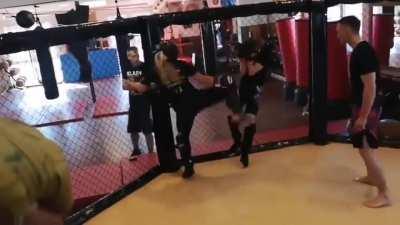 Girl hit guy with a spinning head kick in a sparring match