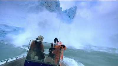 Glacier topples into water near a small boat