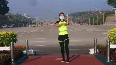 Woman doing her aerobics class without noticing a militar convoy entering the parliment, which happens to be the coup started in Myanmar.