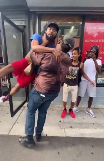 A grown man with a beard getting pinned against a glass window.