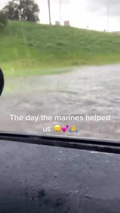 marines in dress uniforms step in to move a car stuck in a flooded road