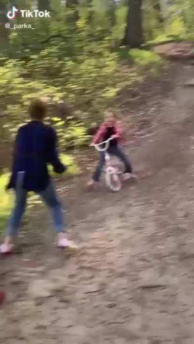 Little kid going downhill on her bike almost takes out her baby sibling.