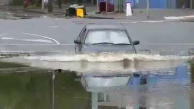Driver ignores warnings from bystanders and drives into a flooded underpass.