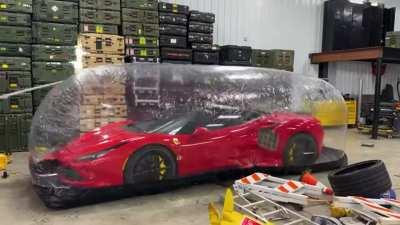Ferrari survives a barrage of tools getting thrown at it inside a plastic storage bubble