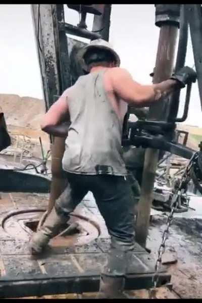 Oil rig worker ”throwing the chain” (a dangerous method of connecting the drill pipes)