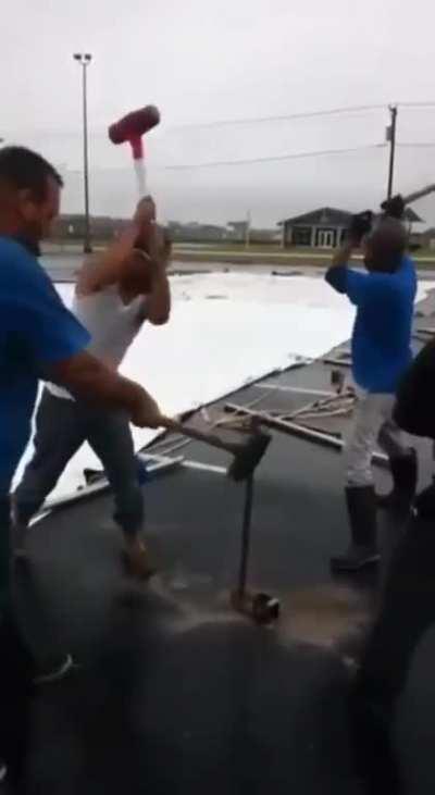 4 men rhythmically pounding a hard steel rod deep into the ground.