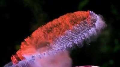 A tennis racquet covered in powder hit with a ball in slow motion