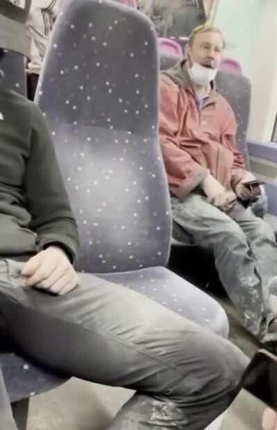 Man on train without headphones plugged in