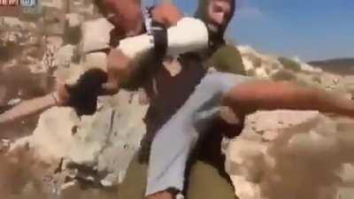 An armed Israeli soldier tries to arrest a Palestinian child by sitting on him and suffocating him without any consideration to the child's crying and pain from his broken hand. The child's family succeeded in ridding him from the soldier later. By: @‌‌‎R