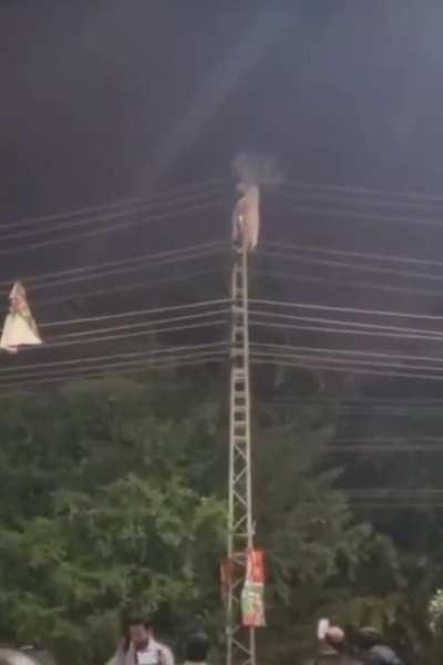 Man climbs a poll during an anti government protest in Pakistan