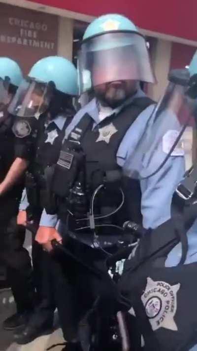 A wall of Chicago police officers with no name tag (or covered name tag) and no body camera
