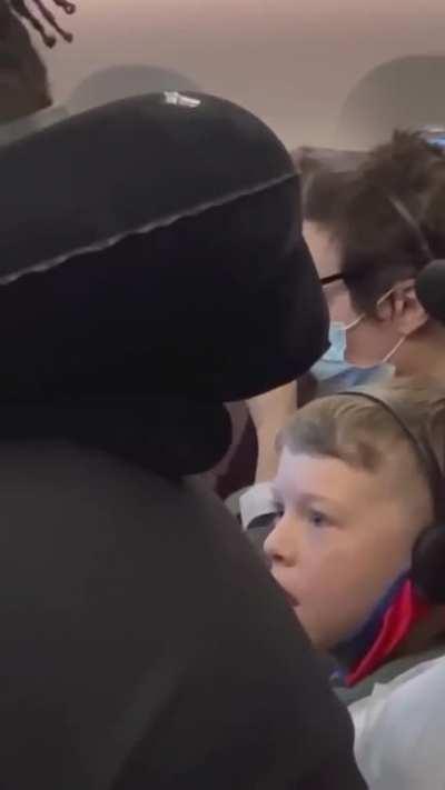 This kid on an airplane watching this dudes tv in absolute disbelief 