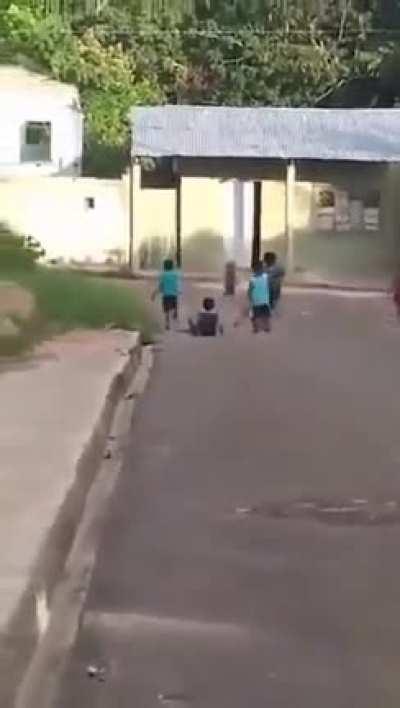 Kids playing rolling a tire down a slope until it collides with a door of a house