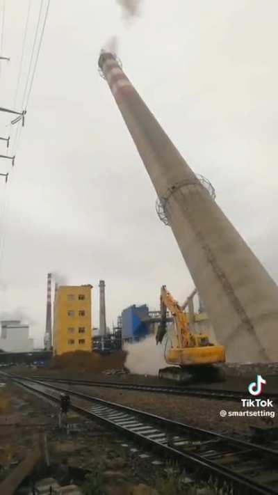 Demolition of smokestack ends with a nearby building struck. Unknown date/location.