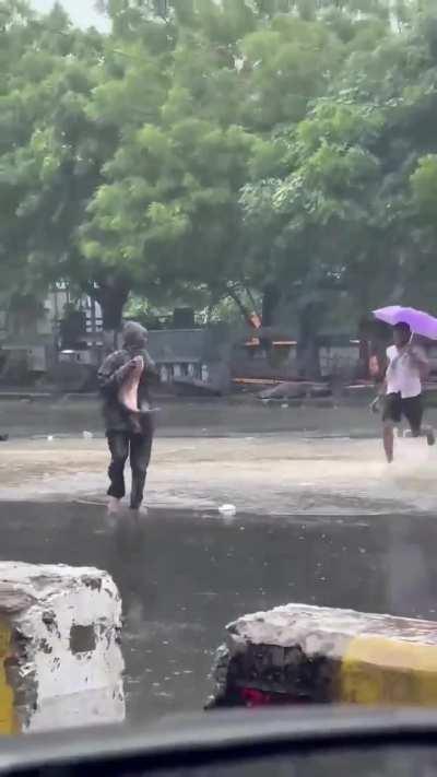 a man catching a fish in the middle of the street amongst one of the biggest rain water floods in the past 34 years at chennai.