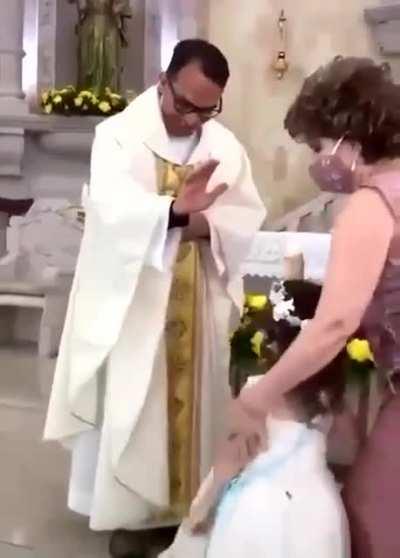 Kid gives high five to priest during blessing.