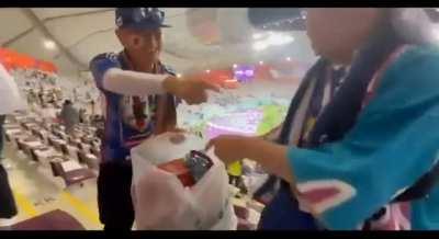 Japanese fans taking out garbage from the bags and littering the stadium