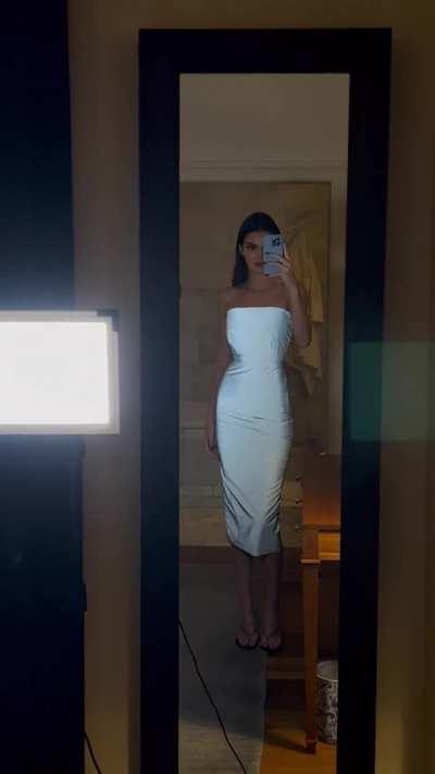 Checking herself out in a white dress