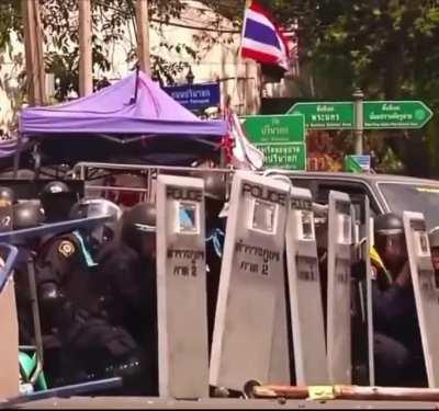 Thai Police officer kicks a live grenade during protests