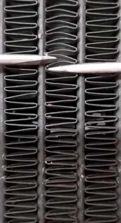 Using 2 screwdrivers to fix radiator.